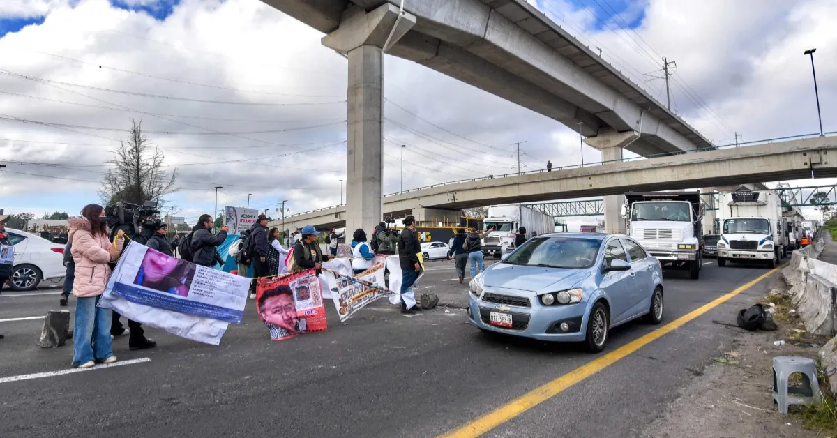 Una vialidad con un segundo piso en donde hay automovilistas parados. Hay al menos 5 personas con lonas.jpg