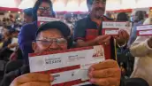 Adultos mayores sostienen un sobre de Programas del Bienestar.