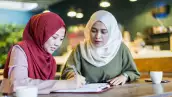 Dos mujeres musulmanas modernas estudian en un café. 