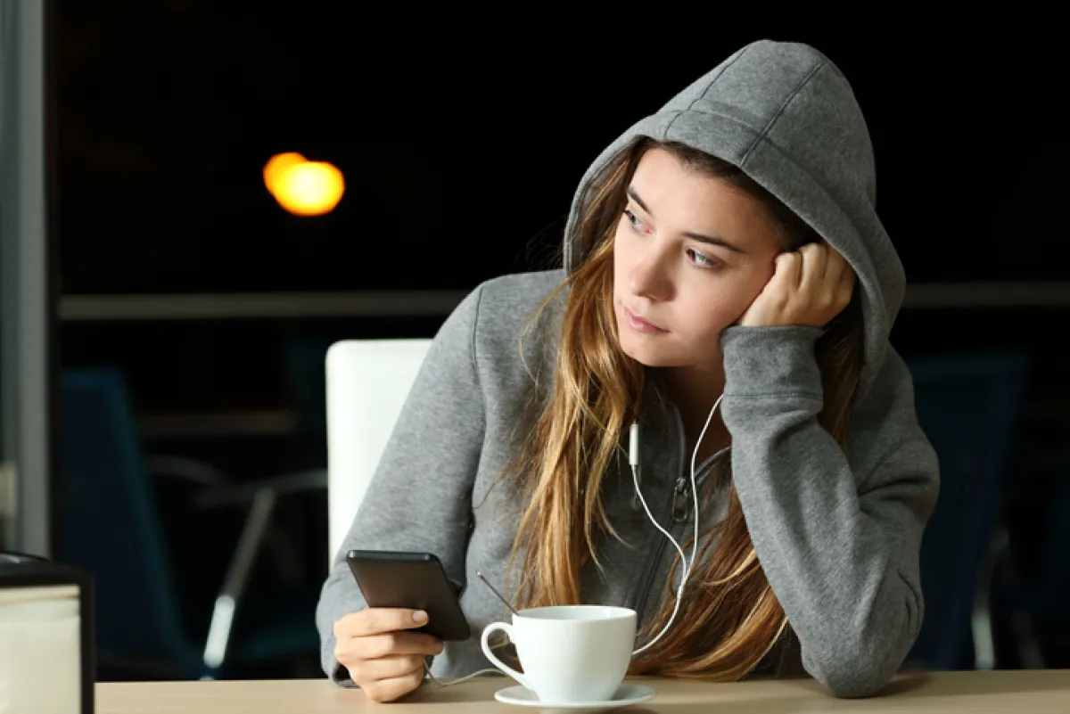 Sad teenager listening to music in a bar