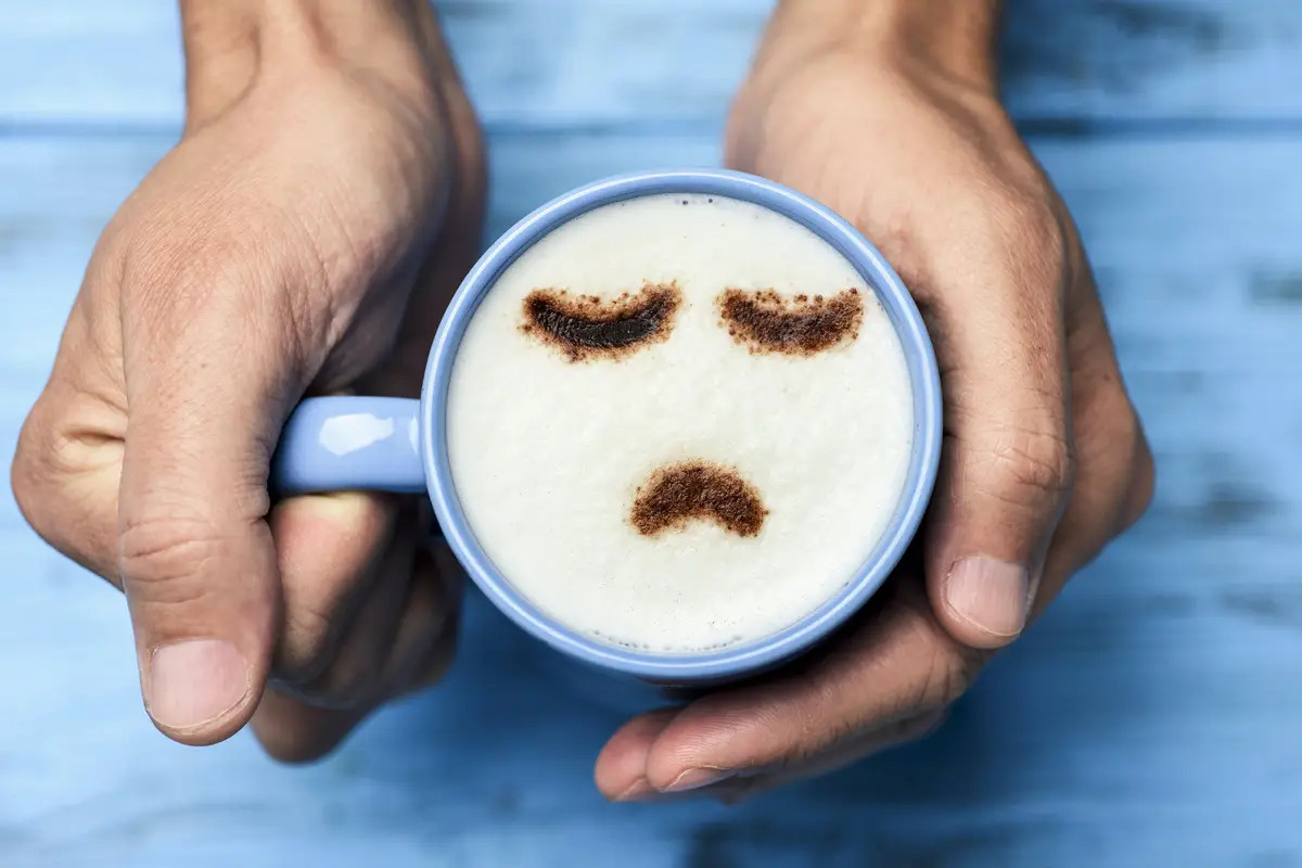 Unas manos sostienen una taza con una cara triste, en referencia al blue monday, el día más triste del año. 