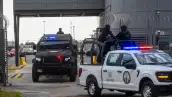 En la imagen se observan patrullas custodiadas por policías armados.