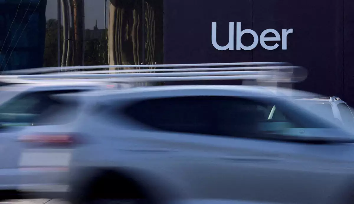 (Coches circulan frente a un anuncio de Uber)