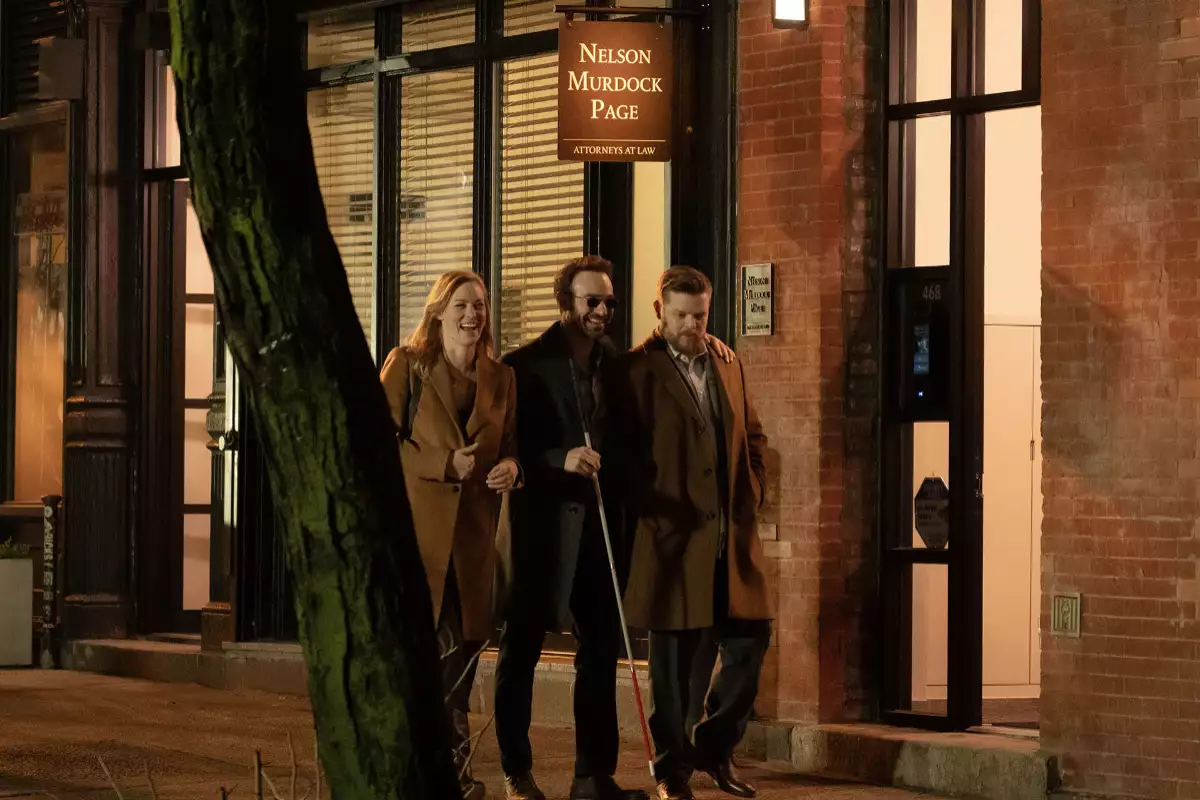 Foto de una escena de Daredevil: Born Again con Deborah Ann Woll, Charlie Cox y Elden Henson como sus personajes Karen Page, Matt Murdock y Foggy Nelson caminando por las calles de Nueva York y un letrero sobre sus cabezas que dice "Nelson, Murdock & Page".