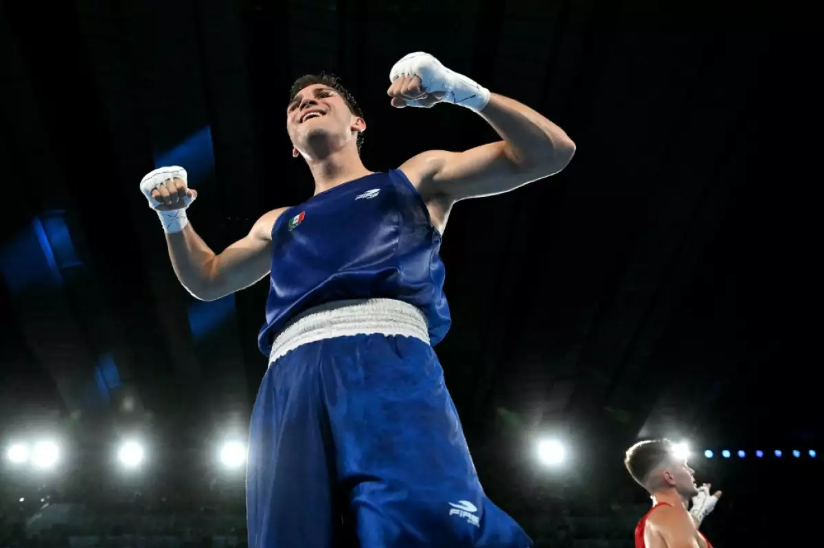Foto de Marco Verde visto de abajo hacia arriba el boxeador levanta los brazos en señal de victoria.