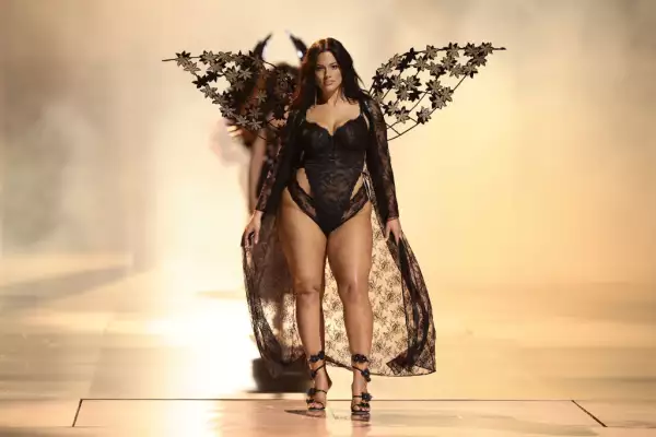 Foto de la modelo Ashley Graham con un body completo de lencería negra y alas de Victoria's Secret Fashion Show.