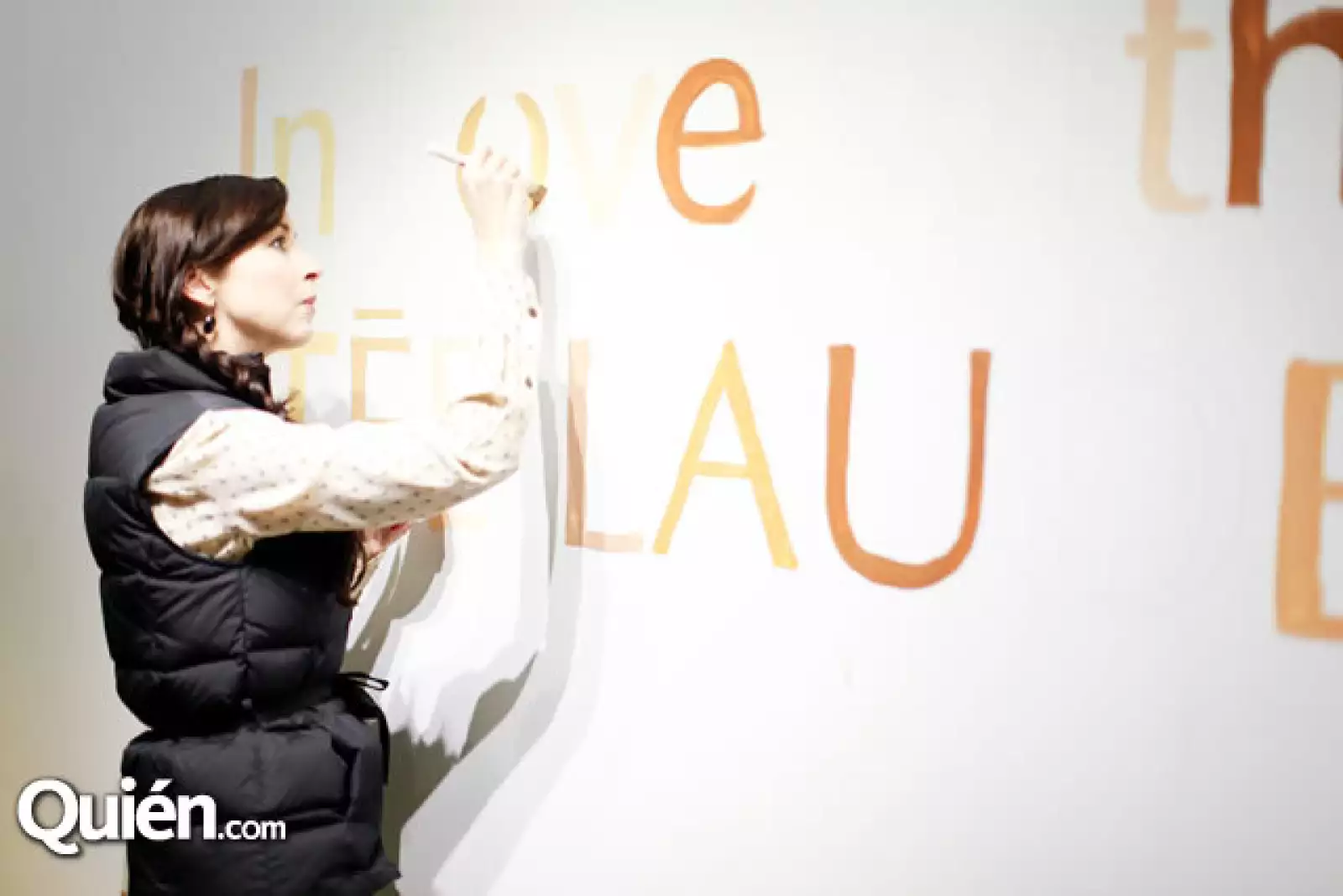 Andrea Torre pintando en una pared la leyenda %u201CIn Love With Estee Lauder%u201D