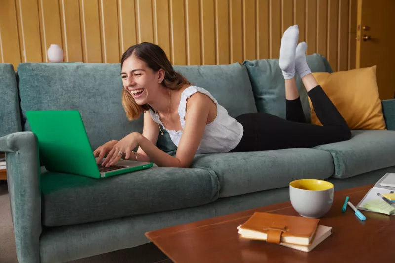 chica sonriendo en sillón con computadora
