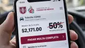 Primer plano de la pantalla de un celular con la plataforma de tránsito de la Ciudad de México abierta, donde aparece el mensaje “pagar multa completa” y un descuento del 50% tachado.