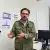 Zoé Robledo, director general del IMSS, habla frente a una cámara en un consultorio médico, con equipo de atención y una computadora al fondo.