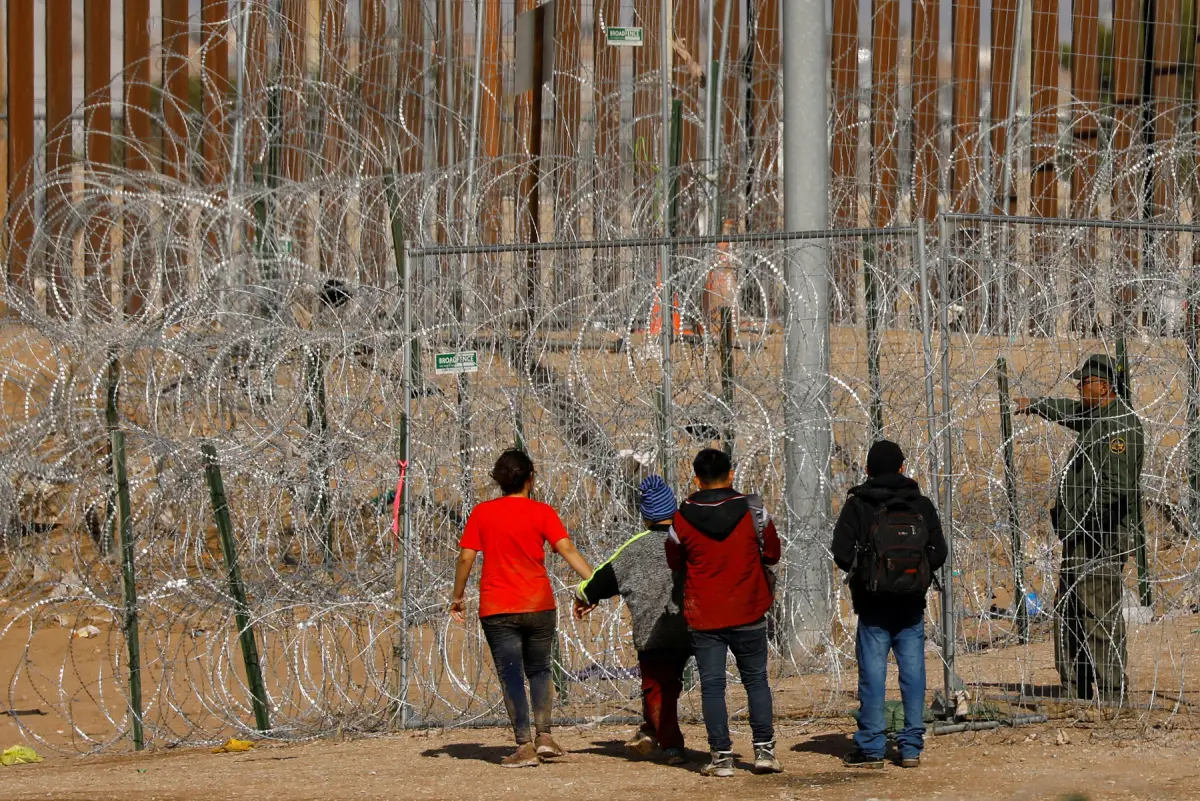 Migrantes que buscan asilo en los EE. UU. se reúnen cerca de alambre de púas instalado para impedir el cruce de migrantes a los EE. UU., mientras buscan ser procesados por la Patrulla Fronteriza de los Estados Unidos en El Paso, Texas, visto desde Ciudad Juárez, México, el 23 de enero. 2024.
