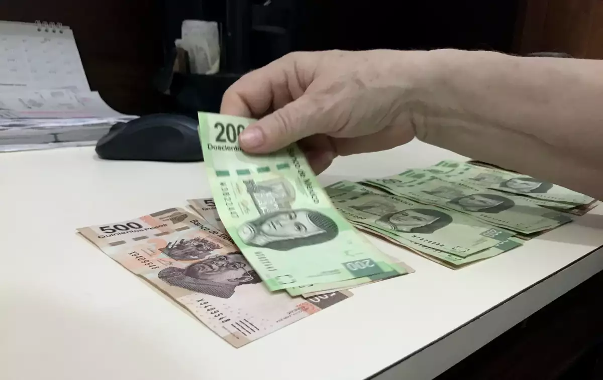 (Una mujer cuenta billetes mexicanos)