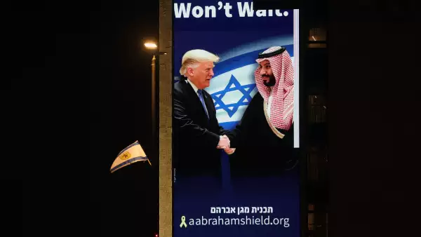 Una valla publicitaria con una imagen del presidente de Estados Unidos, Donald Trump, estrechando la mano del príncipe heredero saudí, Mohammed bin Salman, con el lema encima: «history won't wait » "la historia no esperará"