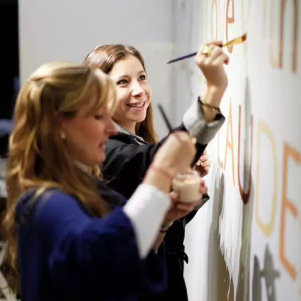 Invitadas pintando en una pared la leyenda %u201CIn Love With Estee Lauder%u201D