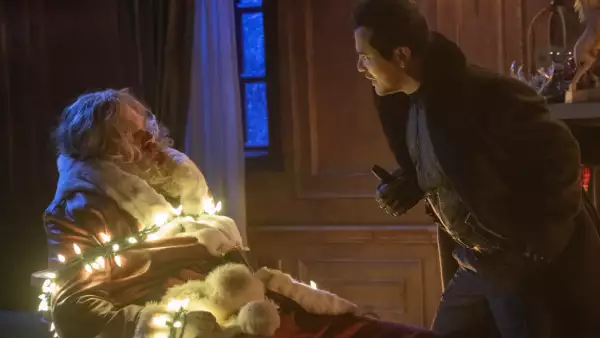 foto de una escena de la película 'Navidad sin Paz' con Santa Claus amarrado con una serie de luces encendidas y enfrente de él un ladrón.