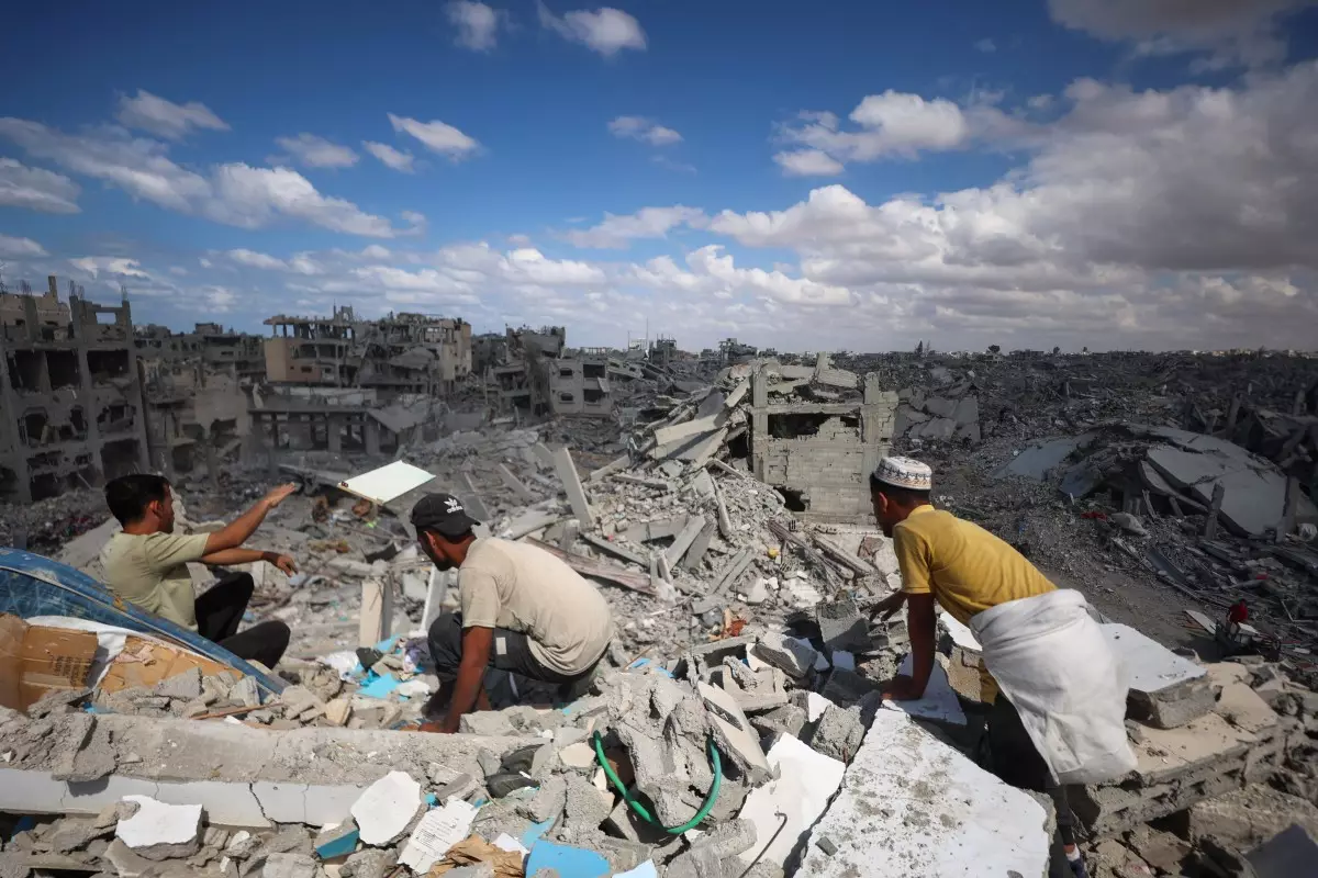 Los palestinos registran los escombros de los edificios en medio de la destrucción generalizada debido al bombardeo israelí en Khan Yunis, en el sur de la Franja de Gaza, mientras se celebra un alto el fuego el 12 de octubre de 2025. Un alto el fuego en Gaza se celebraba por tercer día el 12 de octubre, antes de un intercambio de rehenes-prisisioneros propuesto por Estados Unidos y una cumbre destinada a trazar un camino hacia la paz después de dos años de guerra.