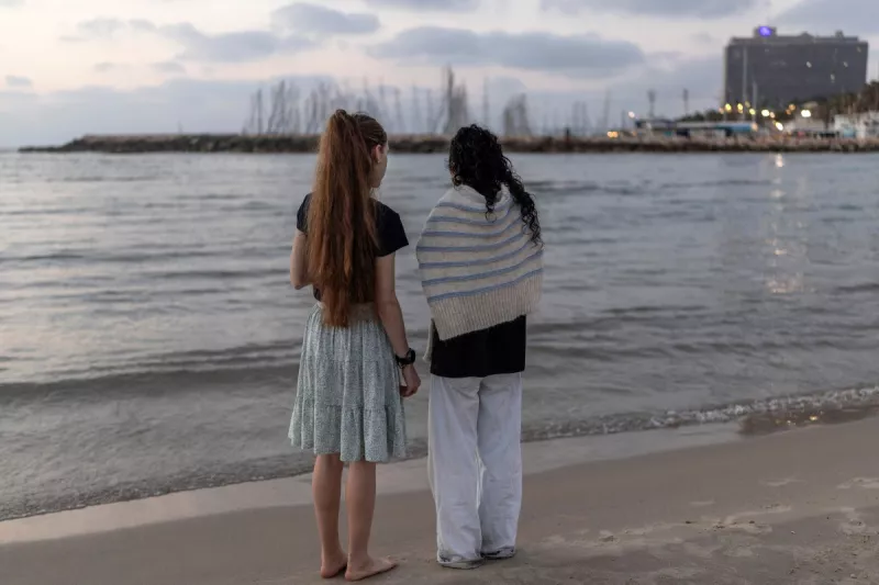 Mujeres de pie a lo largo de una playa al atardecer en Tel Aviv el 8 de junio de 2026. Irán e Israel dijeron el 8 de junio que las hostilidades entre ellos se habían detenido, después de que los dos países intercambiaran ataques que amenazaban con reavivar la guerra de Oriente Medio.