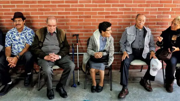 Varias personas de la tercera edad sentadas en sillas, algunas de ellas con bastón. 