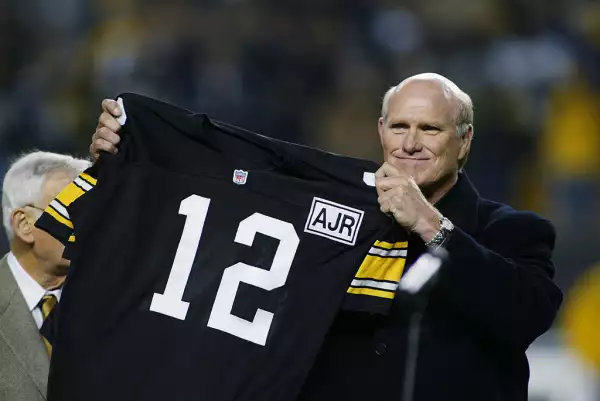 foto de Terry Bradshaw mostrando la playera de los Steelers ya como jugador retirado.