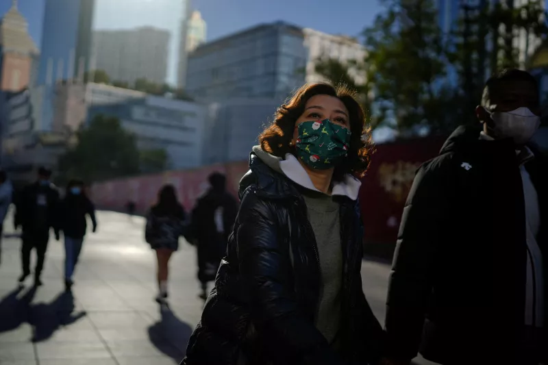 Gente usando mascarillas protectoras caminan en un distrito comercial en Shanghai, mientras China regresa a trabajar a pesar de que el brote de covid-19 continúa. 