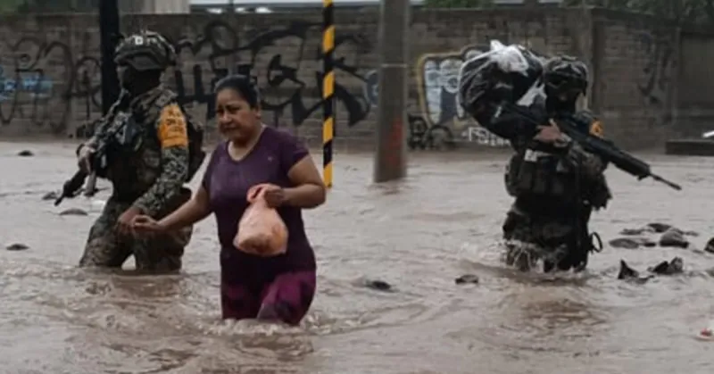 Dos integrantes del ejército ayudan a una mujer en medio de inundaciones.jpg