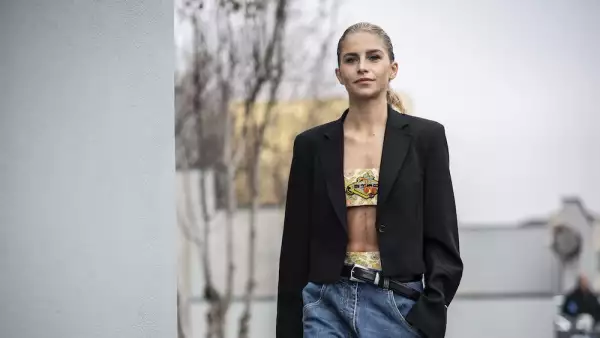 Mujer con top colorido y blazer negro. 
