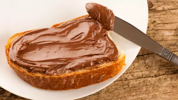 Slice of bread with sweet chocolate nougat spread white plate
