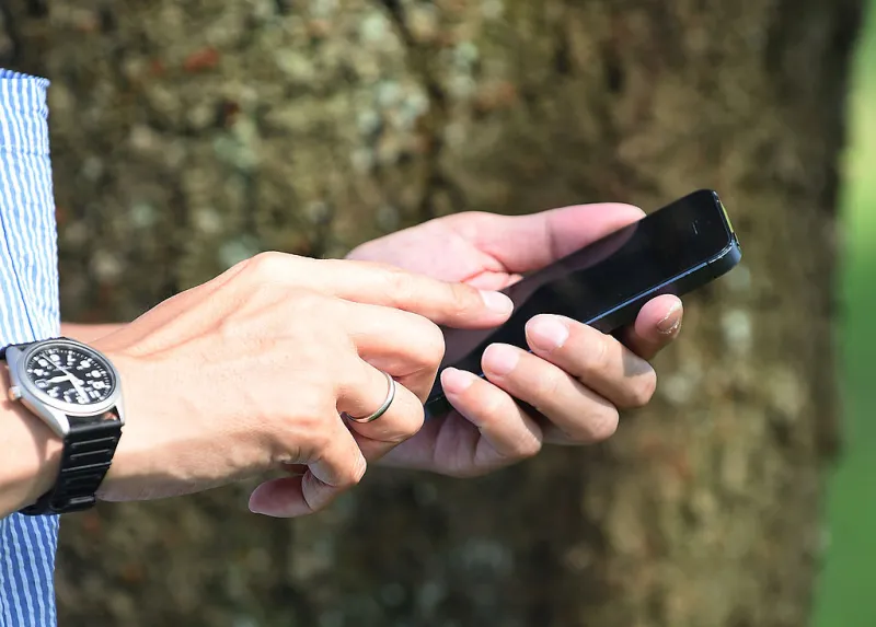 Una persona donde solo se ve su mano que está sosteniendo un teléfono para llamar