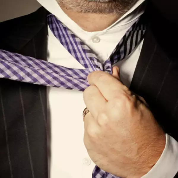 Sostener el nudo con una mano y pasar el extremo ancho por detrás, envolviendo el nudo, hacia el lado derecho.