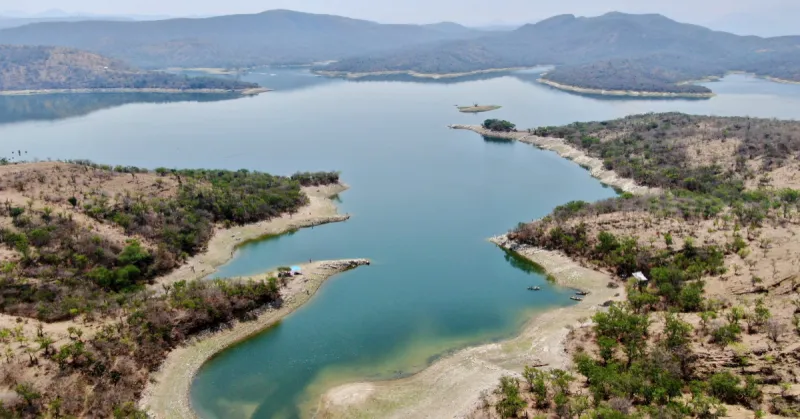 Un cuerpo de agua de diferentes tonalidades de azul en medio de zonas semiáridas y montañas con cielo azul.jpg