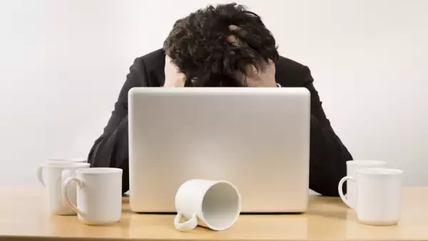 Stressed businessman at desk with several empty coffee cups