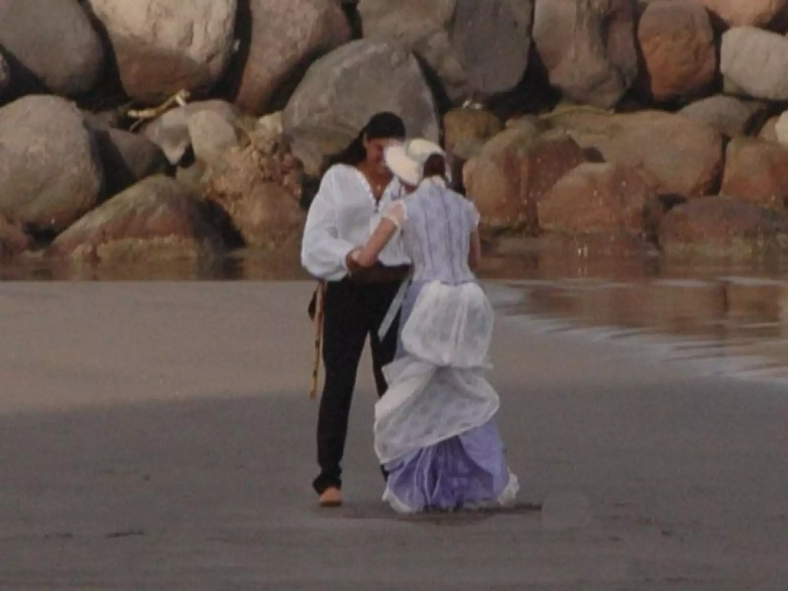 Caminar en la playa debe ser un tanto incómodo con los vestidos que lleva, por eso es socorrida por su equipo de trabajo.