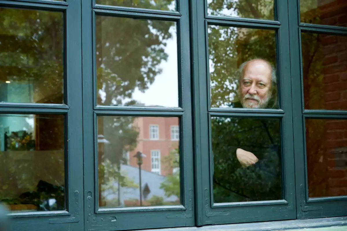 Foto del escritor húngaro Laszlo Krasznahorkai detrás de una ventana posando para la cámara