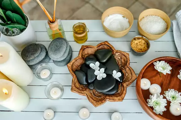 Piedras calientes, toallas, sal áspera y un tazón de agua sobre una mesa en un spa vacío.