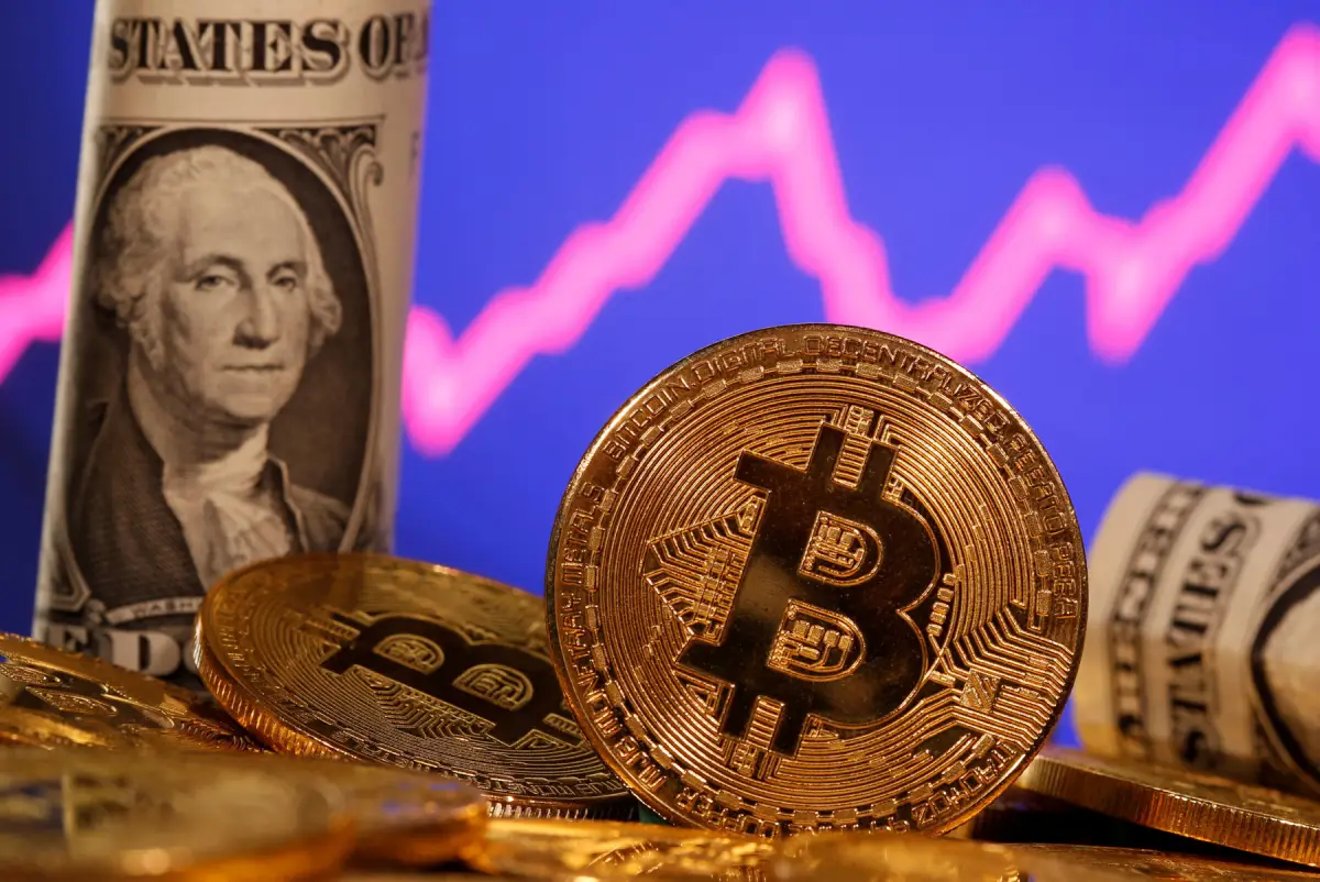 FILE PHOTO: A representation of virtual currency Bitcoin and U.S. One Dollar banknote are seen in front of a stock graph in this illustration