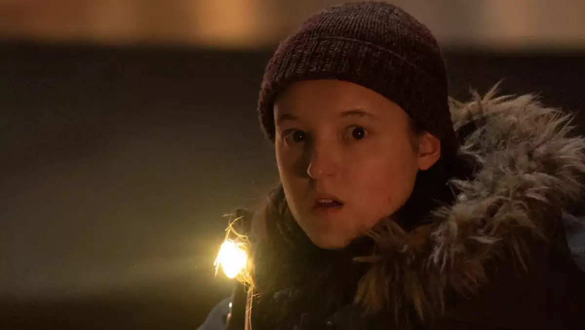Foto de Bella Ramsey como Ellie en una escena de The Last of Us, viste gorro y chamarra invernales y mira a la cámara con expresión de angustia.