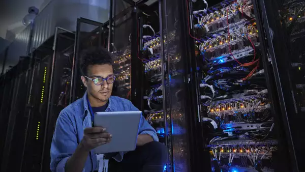 Focused male IT technician using digital tablet in dark server room