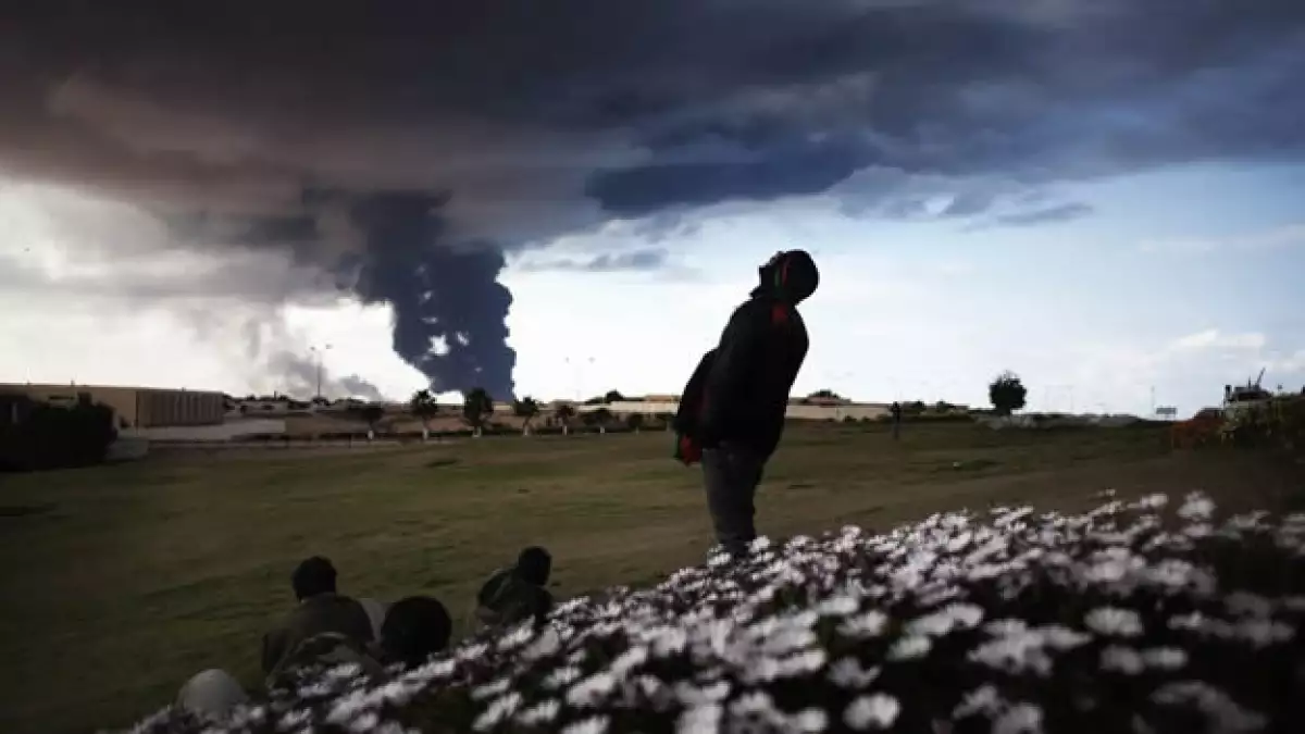 rebeldes observan una nube de humno negro en ras lanuf