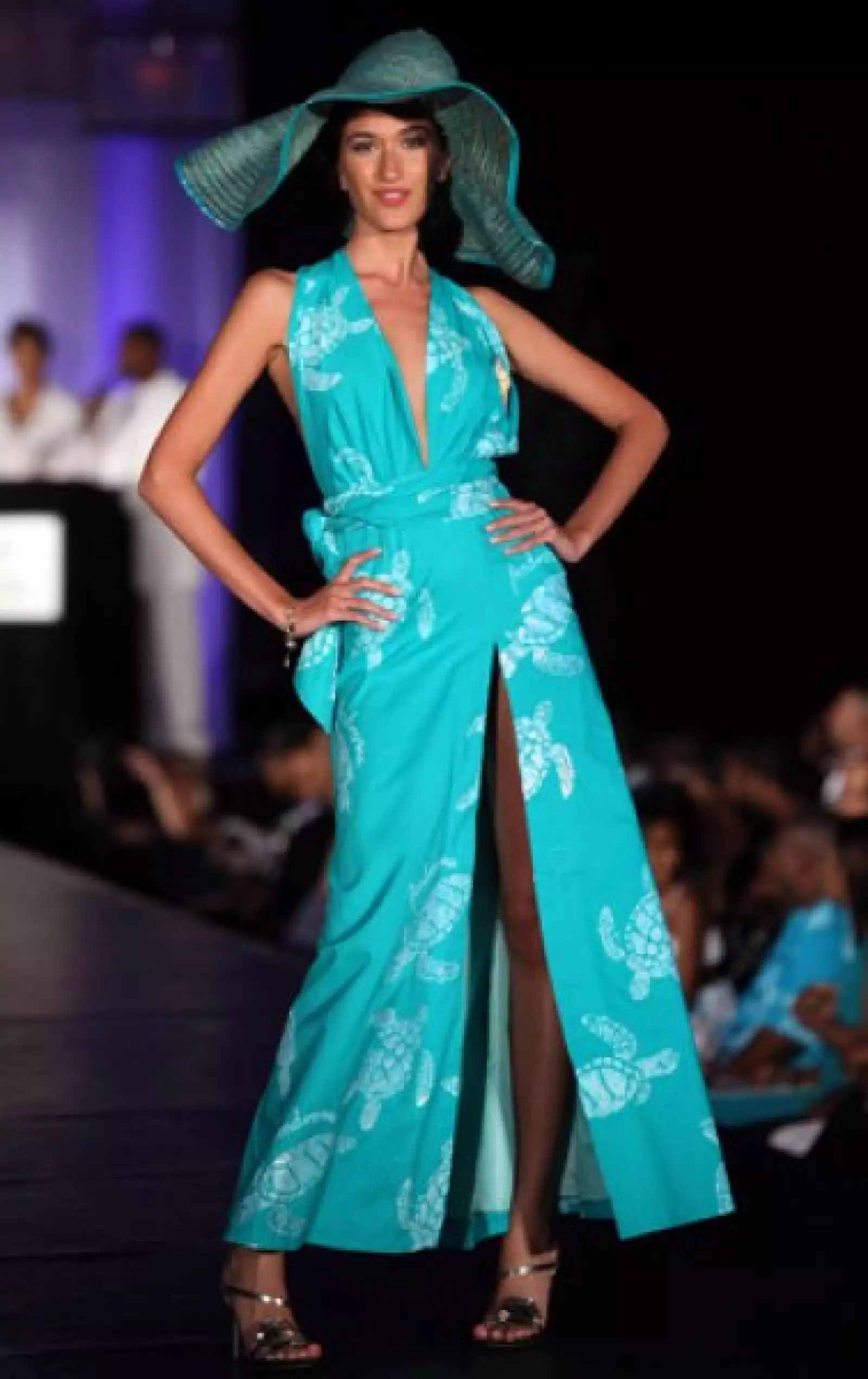 Lika Orjonikidze, de Giorgia, en un vestido largo en color azul verdoso con gran apertura en la pierna, además de un gran sombrero a tono.