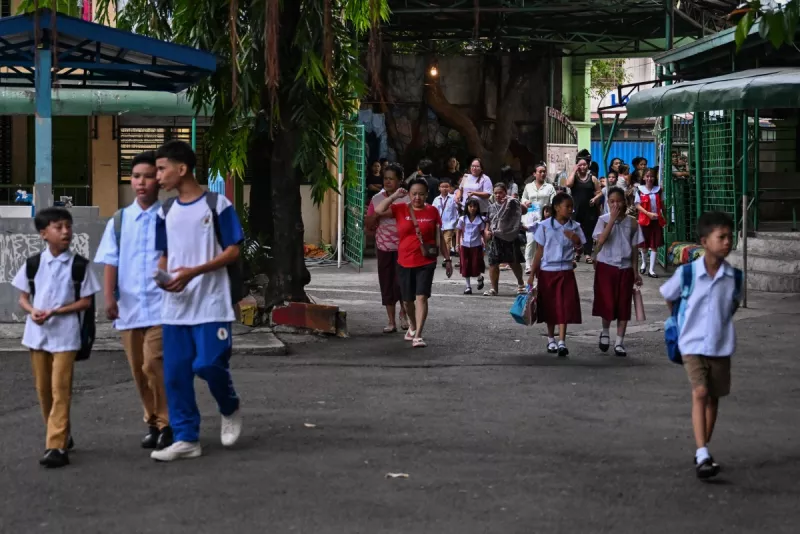 Los padres acompañan a sus hijos mientras las clases se abren para el nuevo año escolar en una escuela primaria en Manila el 8 de junio de 2026.