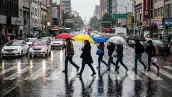 Personas cruzan la calle en CDMX con fuertes lluvias.
