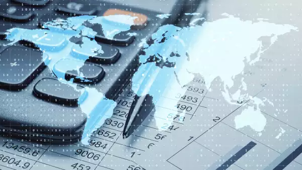 Calculator, pen, and world map overlay on financial data sheets, representing global business and digital accounting concepts.