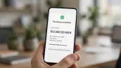 Una mano sosteniendo un celular en el que se lee que se ha recibido una transferencia bancaria correctamente, en el fondo se puede ver una oficina.