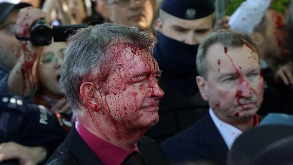 Russia's ambassador to Poland Sergey Andreev is covered in red substance thrown by protesters as he came to celebrate Victory day at the Soviet Military Cemetery in Warsaw