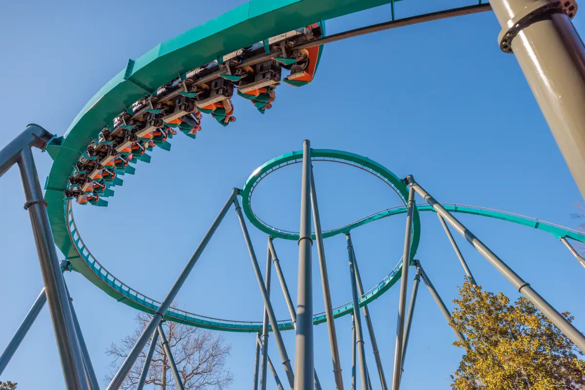 Montaña rusa Goliath de Six Flags con pasajeros recorriendo una curva elevada bajo un cielo despejado.