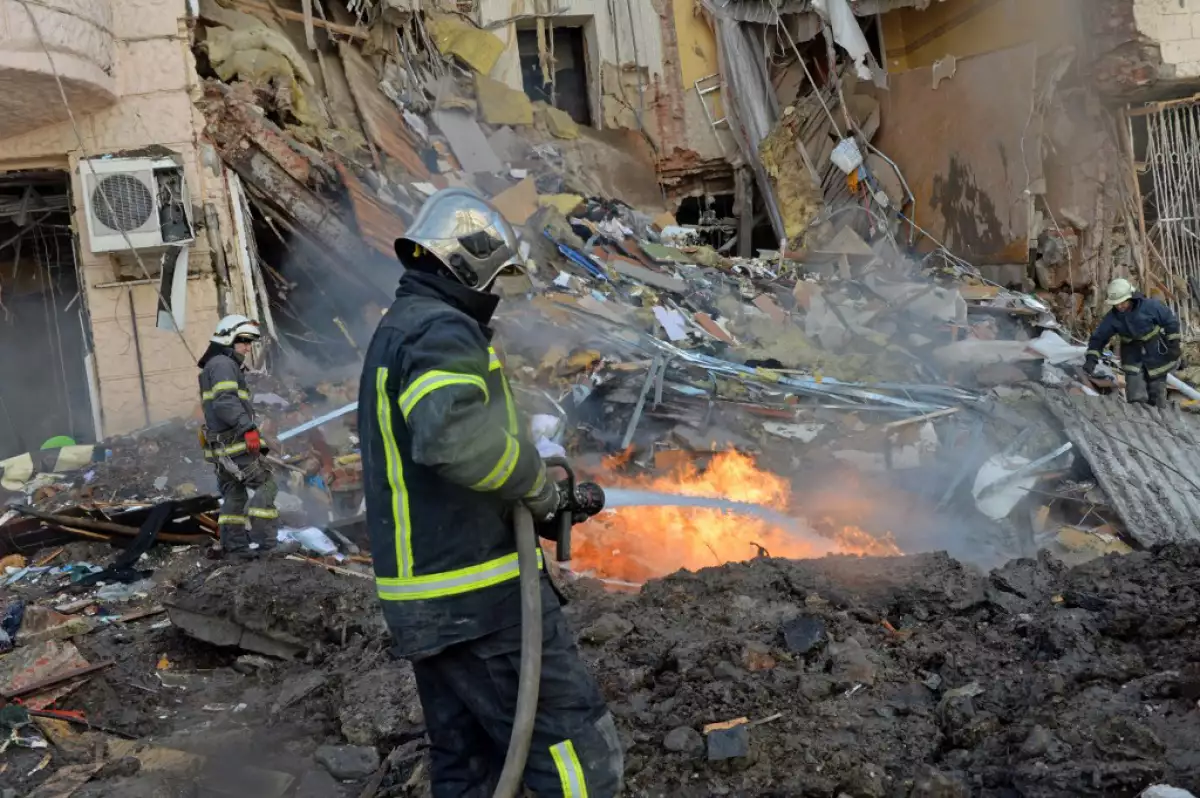 (bomberos trabajan para limpiar los escombros y extinguir un incendio en un edificio gravemente dañado después de que un cohete ruso explotara en las afueras de la segunda ciudad de Ucrania, Kharkiv)