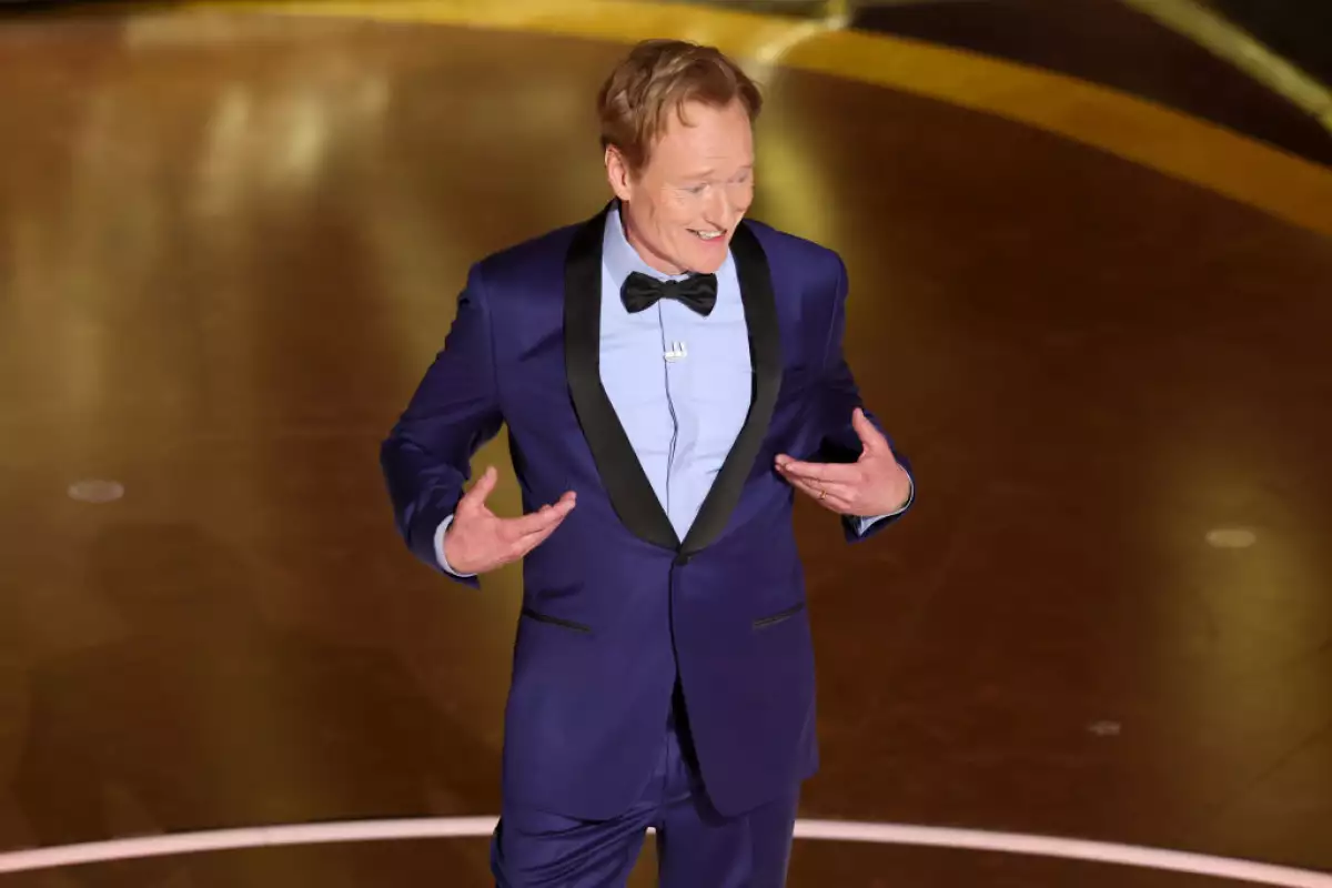 Foto de Conan O'Brien con un traje color morado intenso y un moño negro durante su presentación en los Oscar 2025.