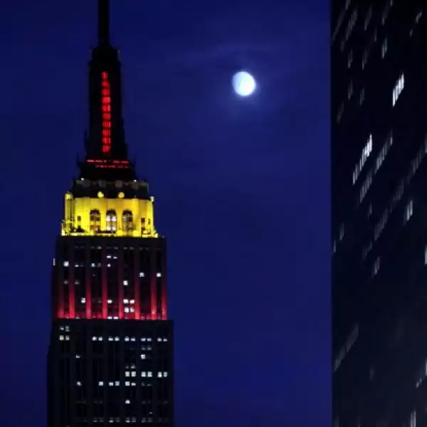 La luna llena resplandece en el cielo de Nueva York al lado del Empire State, el cual está iluminado en amarillo y rojo en honor al 60 aniversario de la China comunista.