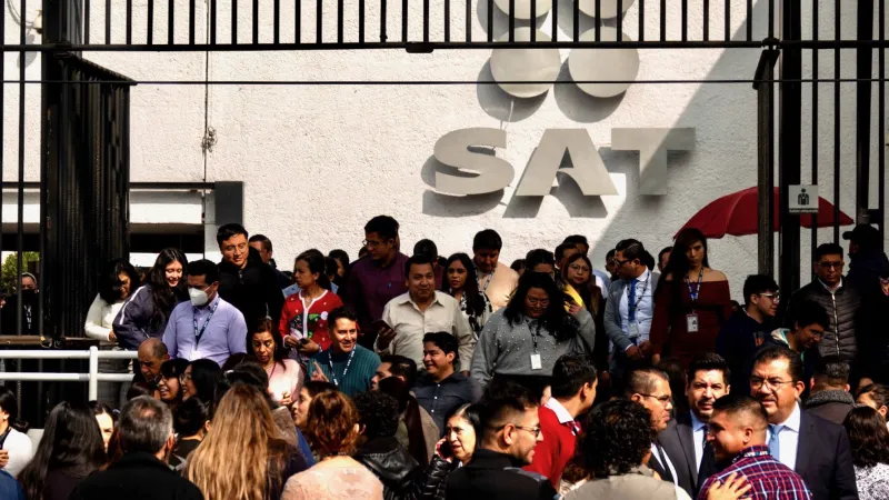 En la imagen se aprecia a trabajadores del SAT haciendo fila para entrar a las oficinas. 