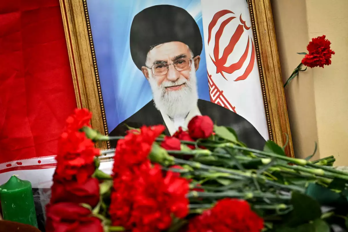 This photograph shows flowers laid at a makeshift altar with a portrait of late Iran's supreme leader Ayatollah Ali Khamenei and a flag of the Islamic Republic of Iran outside the Iranian Embassy in Russia, in Moscow on March 2, 2026. Russian President on March 1 slammed the United States and Israel's killing of Khamenei as a "cynical violation" of morality and law. Tehran has stood by as one of Russia's closest allies throughout Moscow's Ukraine offensive, and the Kremlin had earlier called for restraint in the run-up to the US-Israeli strikes on Iran. 